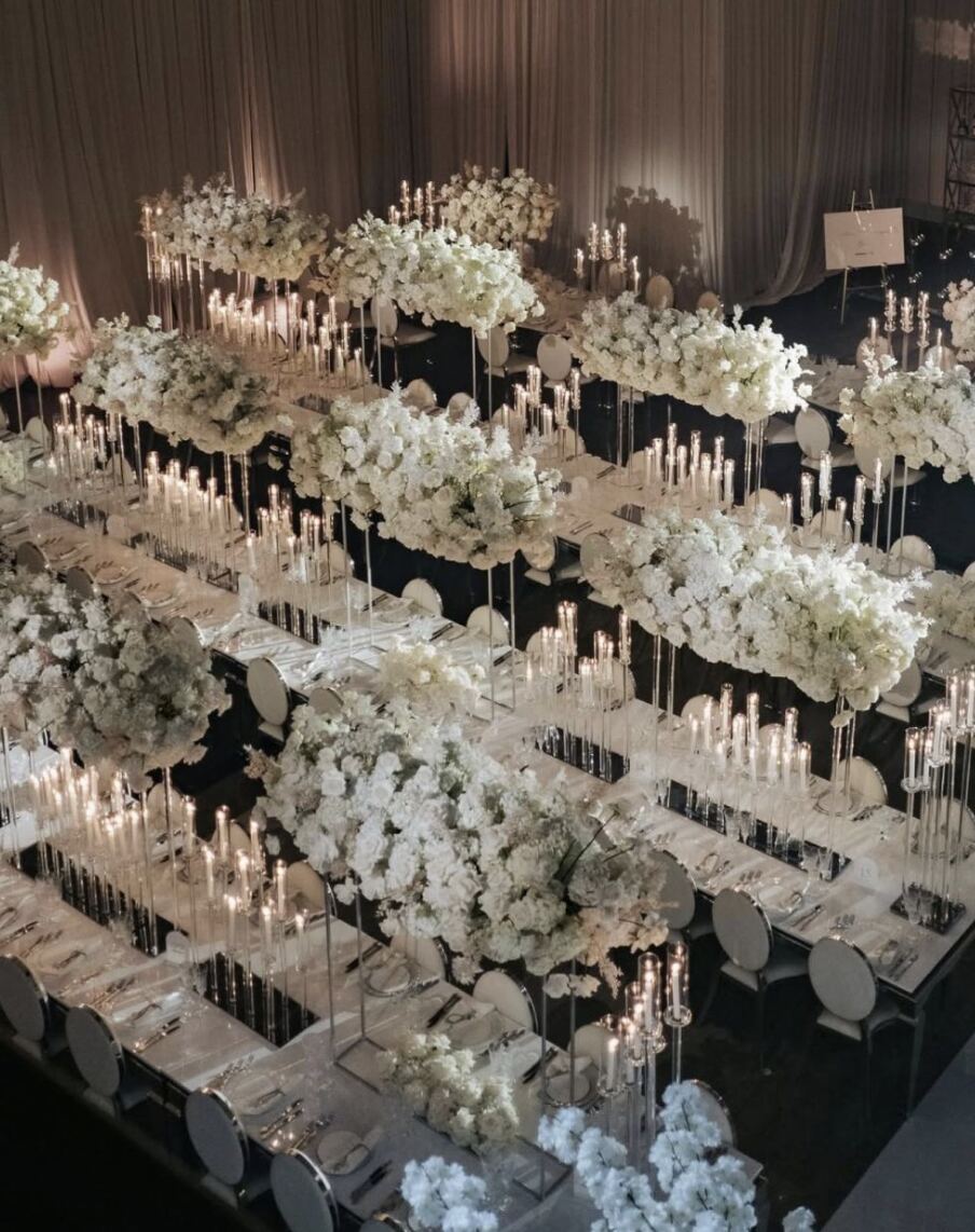 All-White Elevated Tablescape - Suspended white floral clouds and crystal taper candelabras over mirrored long tables by Aura Floral Design Miami