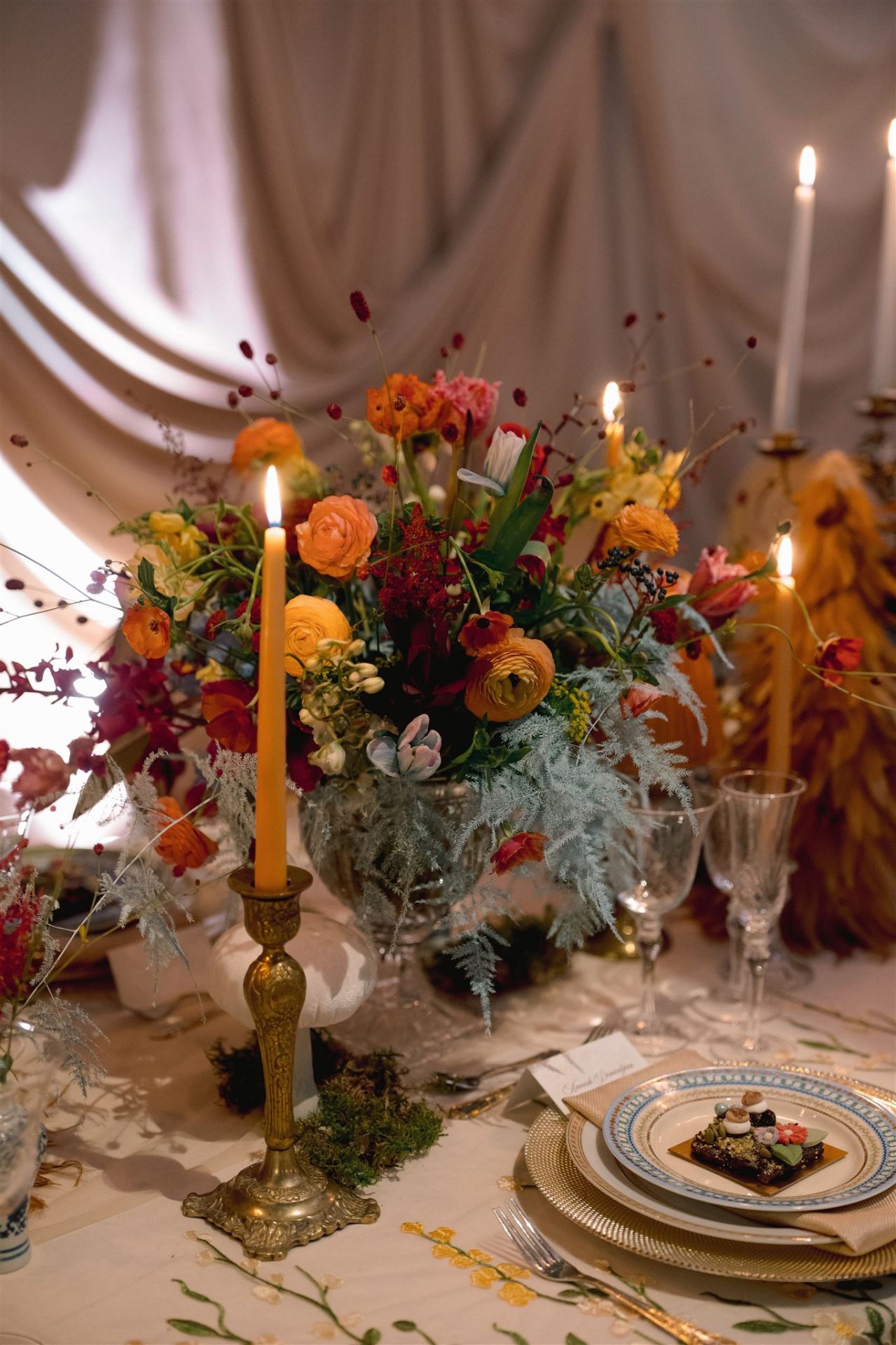 Candlelit Garden Tablescape - Layered ranunculus in burnt orange, blush, and amber with heirloom brass and drifting tapers by Aura Floral Design Miami
