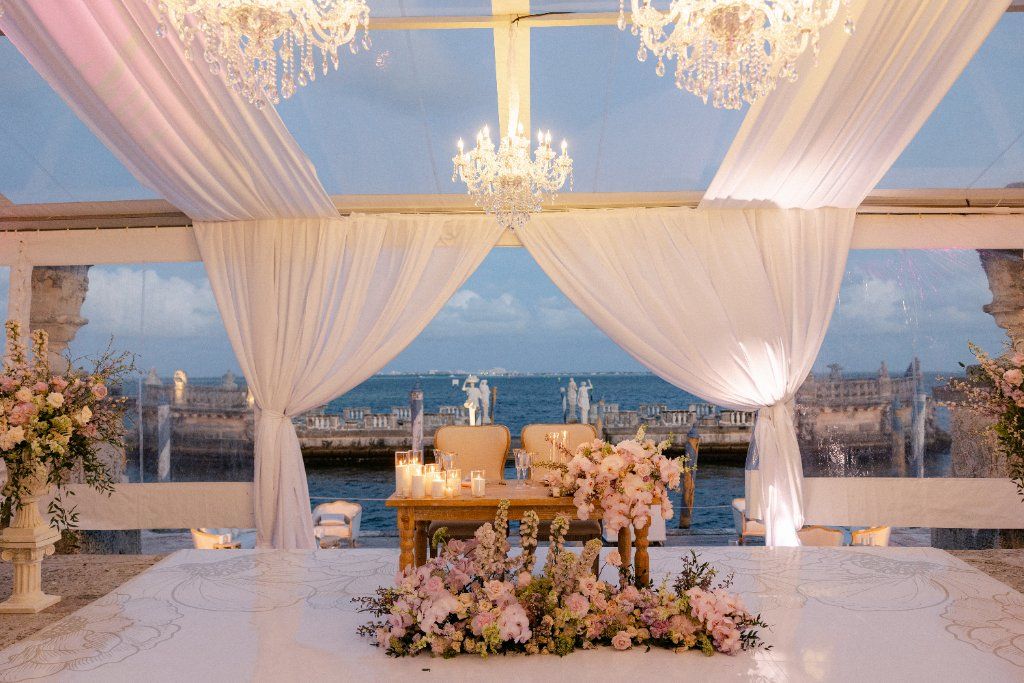 Sweetheart Table - Oceanfront reception with cascading florals & chandeliers by Aura Floral Design Miami
